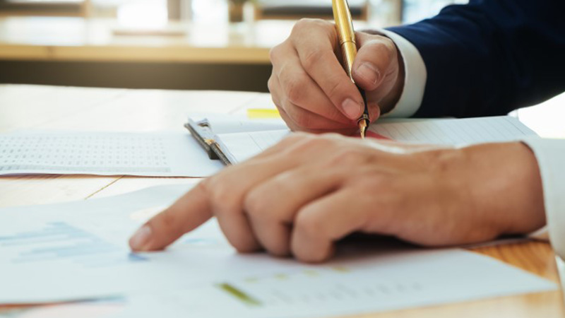 Executive holding a pen and making notes from a report