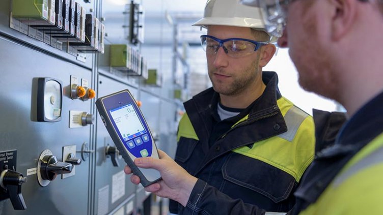 Workers testing for noise in electricity substation