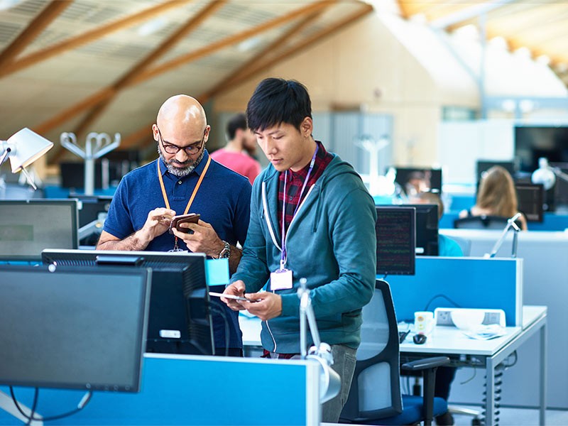 Two men using mobile phones at desk