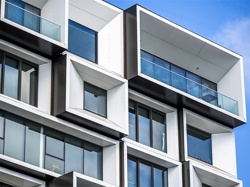 Street scene of the modern city with wall of a multistory apartment building with decorative trimming in the form of squares in geometric grid and protruding modular facade