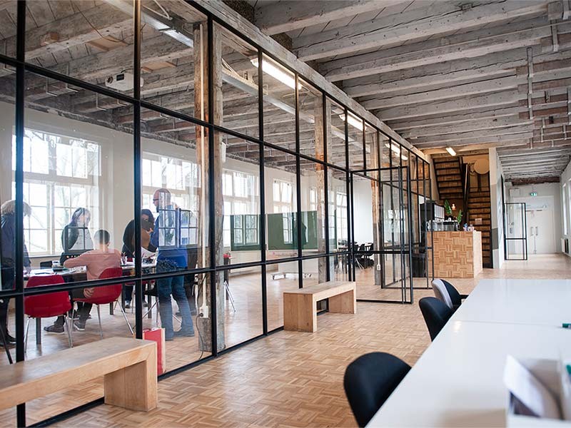 Beautiful modern office space in an old building. A team is working and a woman is making a phone call in the hallway