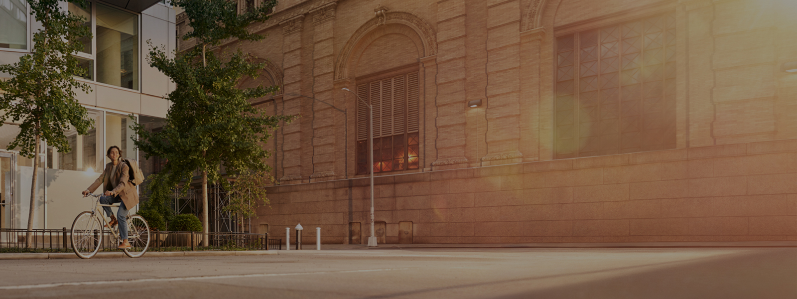 Smiling biker in front of heritage real estate looking into sunlight 