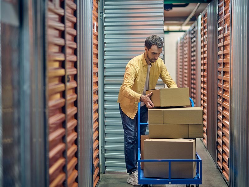 Man loading boxes from a trolley into a self storage unit.