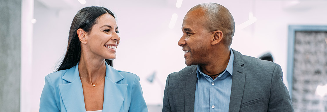 Male and female business colleagues in mentoring partnership discussing workplace strategies