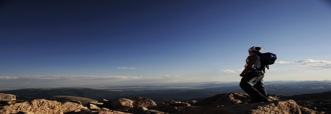 Man stands alone on top of a mountain