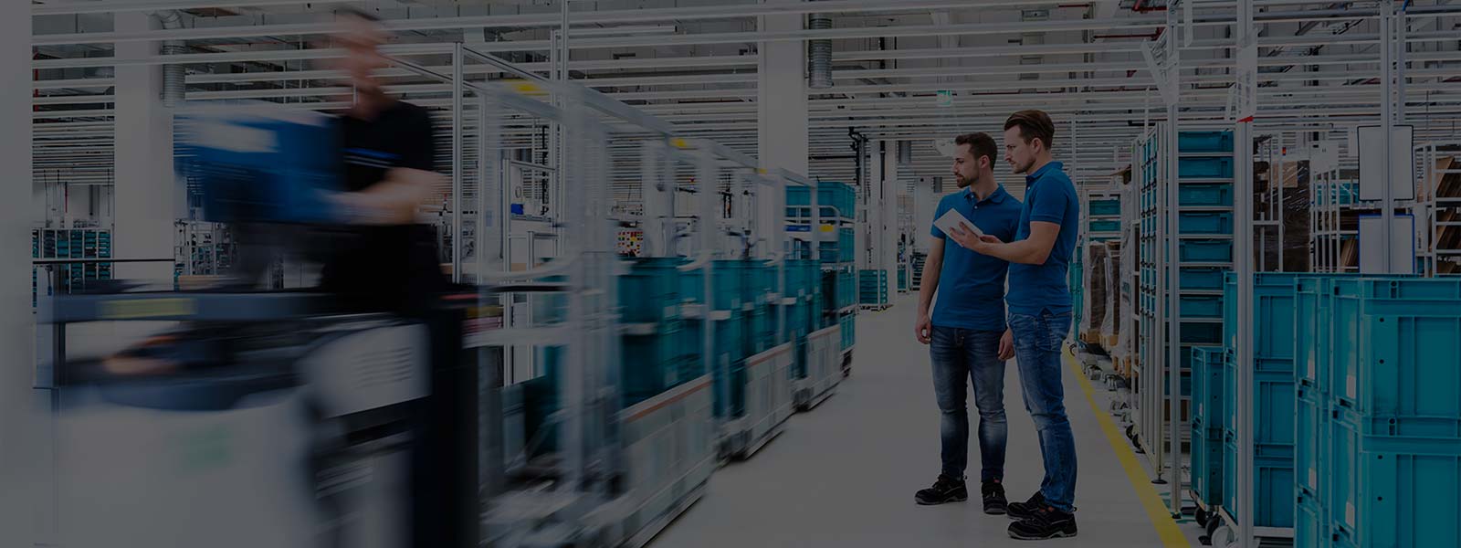 Two men with tablet talking in industrial hall