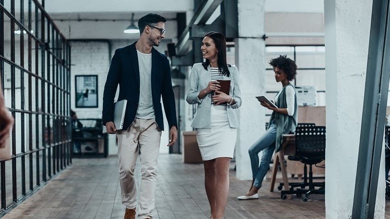 Two employees going towards the meeting room while having a conversation