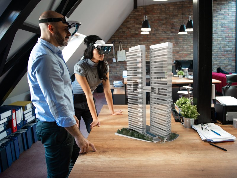 Two people looking at 3d object by using AR glasses.
